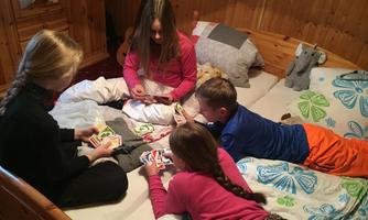 Four children are playing cards on a bed. They are having a lot of fun and are focused on the game.