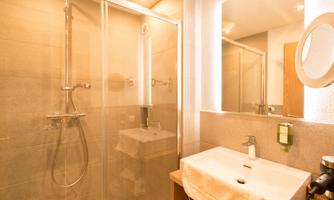 A modern bathroom with a glass shower and an elegant sink. The walls are in soft shades of gray, creating a bright, inviting atmosphere.