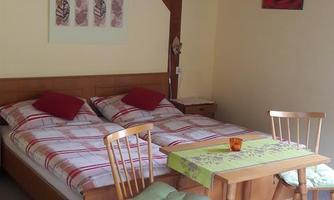A cozy bedroom with a double bed and wooden furniture. A small table with chairs is also available.