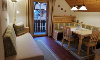 A cozy living space with a seating area and a dining table. Large windows provide access to the balcony and let in plenty of light.