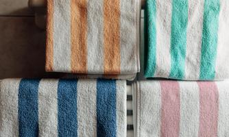 Colorful towels in various colors are stacked on top of each other. They are arranged on a radiator and look fresh and inviting.