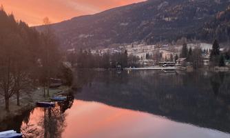 A picturesque lake with an impressive sunset. The vibrant colors are reflected in the calm water and surrounded by gentle hills.