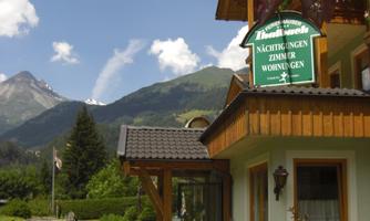A cozy house in a picturesque landscape with mountains in the background. The surroundings are green and inviting, perfect for relaxation and enjoying nature.