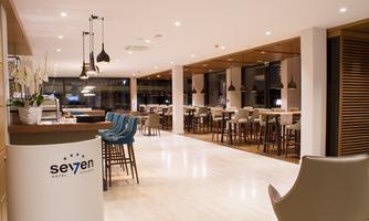 A modern restaurant with bright, minimalist furniture and warm lighting. There are tables and chairs as well as an inviting counter.