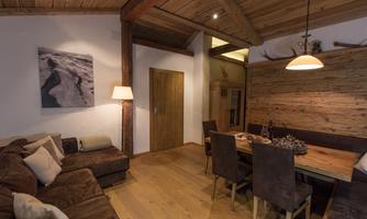 A cozy living room with a comfortable sofa and a dining table.  
Warm wood veneer and soft lighting create an inviting atmosphere.