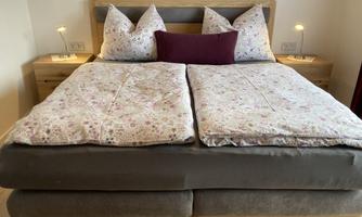 A cozy bedroom with a double bed and decorative cushions. Next to the bed, there are two nightstands with soft lamps.