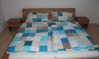 A cozy bedroom with a large bed and colorful blankets. Next to the bed, there are two nightstands.