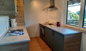 Modern kitchen with bright wood accents and a window that lets in plenty of natural light. The items are neatly arranged, providing an inviting space for cooking.