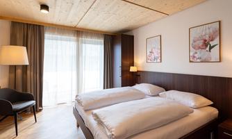 A modern bedroom with a double bed and soft colors. Large windows let in plenty of daylight and give the room an inviting atmosphere.