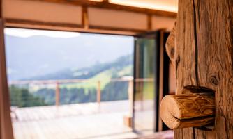 A modern bedroom with wooden details and a view of the mountains. Large windows let in plenty of daylight.