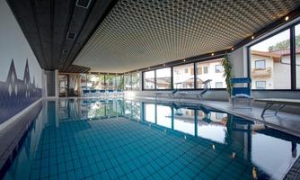 A beautiful indoor pool with clear blue water. Large windows offer a view of the outdoor landscape.