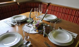 A beautifully set table with white plates and glasses. In the center, there is a floral centerpiece and antlers.