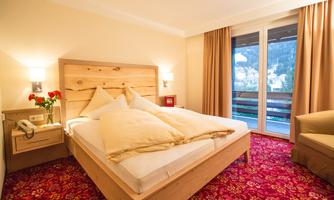 A cozy bedroom with a double bed and a clear view of the balcony. The warm color scheme and the beautiful carpet pattern create an inviting atmosphere.