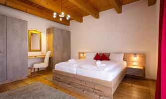A cozy bedroom with a large bed, wooden details, and a table. The warm colors and modern design create an inviting atmosphere.