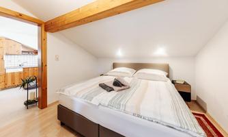A cozy bedroom with a double bed and modern design. The room has bright walls and wooden details that create a warm atmosphere.