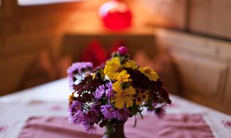 A beautiful bouquet of colorful flowers is on a table. In the background, a cozy atmosphere with warm colors can be seen.