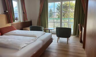 An inviting room with two beds and a modern style. Large windows offer a view of nature and let in plenty of light.