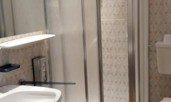 A modern bathroom with a shower cubicle, a sink, and a toilet. The walls are decorated with a light pattern.