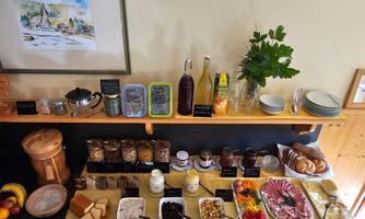 A lavish breakfast buffet with various foods. There is bread, cold cuts, fresh fruit, and drinks on a wooden shelf.