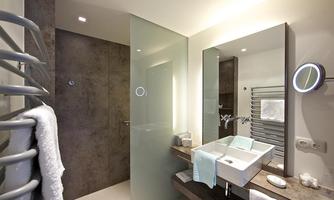 A modern bathroom with a clear shower partition and stylish fixtures. The space is bright and well-equipped with towels and toiletries.