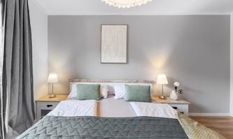 A modern bedroom with a large bed and soft colors. Two nightstands with lamps and decorative wall art give the room an inviting atmosphere.
