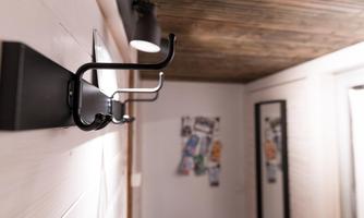 A modern wall hook with multiple hanging options. In the background, there is a mirror and a wall with notes.