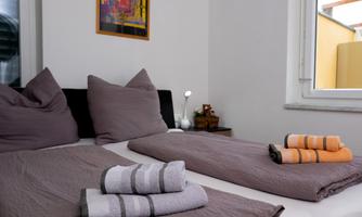 A cozy bedroom with two beds and decorative pillows. Towels are neatly placed on the bedspread.