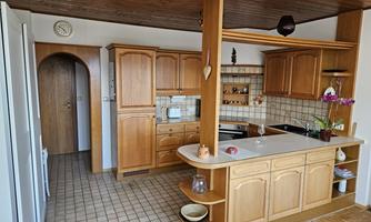 A bright kitchen with wooden cabinets and a countertop. The room is well-equipped and offers plenty of space for cooking.