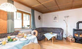A cozy room with a dining area and a couch. Fresh fruit and drinks are arranged on the table, while a fireplace radiates warmth.