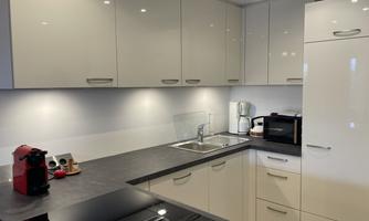 A modern kitchen with bright cabinets and a gray work area. The appliances are functional and well arranged.