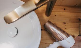 A modern sink with an elegant faucet and a hairdryer beside it. The wooden surface gives the room a warm atmosphere.