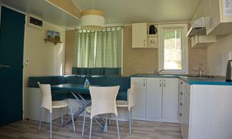 A modern kitchen unit with a dining table and chairs. Bright colors and large windows create a friendly atmosphere.