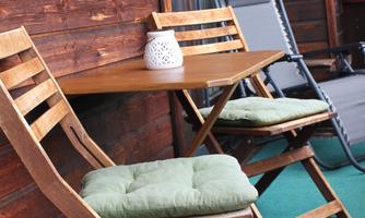 A cozy balcony with a small table and two chairs. Next to the table is a decorative lantern.