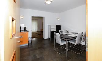 A modern kitchen with a dining area. The room has bright walls and an elegant floor.