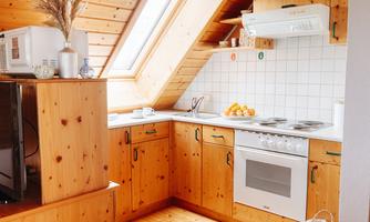 A bright kitchen with wooden cabinets and a large skylight. Fresh fruit and essential kitchen appliances are on the countertop.