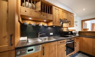 A modern kitchen with wooden cabinets and an elegant black work area. The equipment includes a stove, a dishwasher, and a sink.