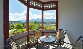 A cozy balcony with a view of the mountains and the surrounding landscape. There is a small table and chairs, perfect for relaxing.