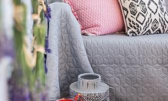 A cozy living space with a gray sofa, many cushions, and decorative lanterns. The atmosphere is inviting and stylish.