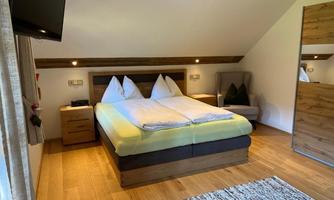 A cozy bedroom with a double bed and two pillows. The room is modernly furnished and has a television as well as an armchair.