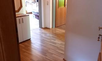 A bright hallway with wooden flooring and open doors that lead to other rooms. The walls are simply and warmly designed.
