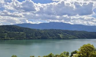 A tranquil landscape with a clear lake and gentle hills in the background. The sky is cloudy, giving the scene a peaceful atmosphere.