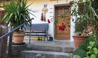 An inviting front door with a sunny decoration and a bench in front of the entrance. Surrounded by plants and flowers, it gives the scene a friendly atmosphere.