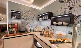A modern coffee bar with various types of tea, snacks, and fresh fruit. The wall is adorned with a creative illustration.