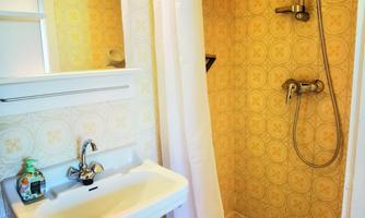 A small bathroom with a shower and a sink. The walls are decorated with a floral pattern.