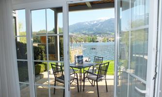 A beautiful viewpoint with a table and chairs by the water. In the background, mountains and a clear sky are visible.