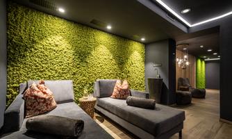 A relaxing space with elegant sofas and a vibrant moss wall. The soft lighting creates a soothing atmosphere.