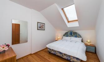 A cozy bedroom with a double bed and a large skylight. The wooden floor and soft lighting create an inviting atmosphere.