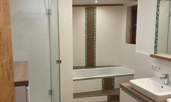 A modern bathroom with a glass shower and a stylish vanity. The walls are bright, and there is a wooden ceiling that adds warmth to the space.