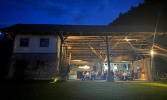 A cozy restaurant with an outdoor area at night. Tables are set, and light sources create an inviting atmosphere.