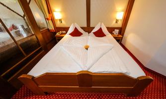 A cozy bedroom with a double bed. The bedding is neatly folded, and the room is decorated in warm colors.